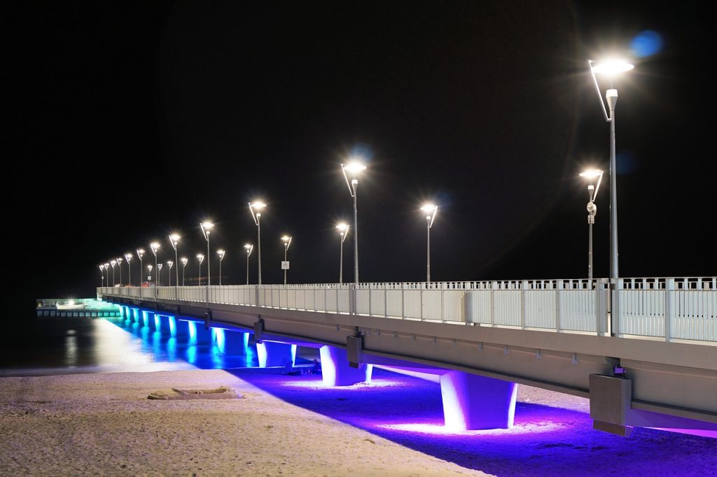 A beautifully lit-up pier in different colours of the rainbow at night. 